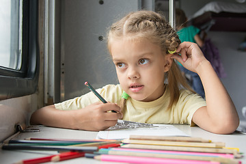 Image showing Six year old girl lost in thought looked out the window drawing pencils in second-class train carriage