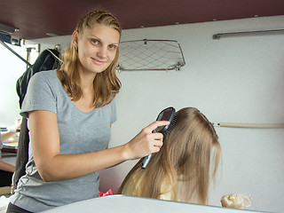Image showing Mother combing daughter\'s long hair on a cot in a train