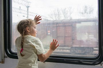 Image showing The girl looks into the distance from the window of a train car