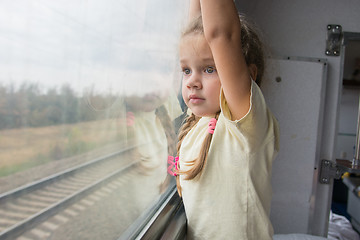 Image showing  Four-year girl with astonishment looks in the window of a train