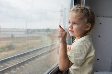 Image showing  Four-year girl shows a finger on something from the window of a train car