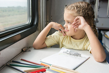 Image showing The girl smiled happily looking out the window drawing pencils in a train