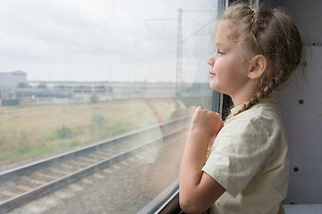 Image showing Four-year girl looks out the window of the train car