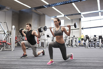 Image showing young man and woman training with barbell in gym