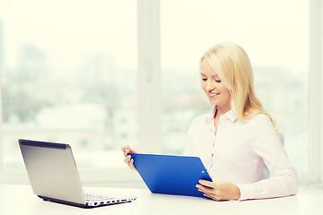 Image showing smiling businesswoman reading papers in office