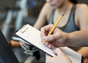 Image showing close up of trainer hands with clipboard in gym