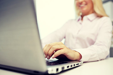 Image showing smiling businesswoman or student typing on laptop