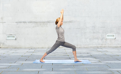 Image showing woman making yoga warrior pose on mat outdoors