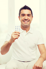 Image showing happy man showing pack of pills at home