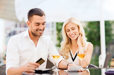 Image showing happy couple with bank card and bill at restaurant