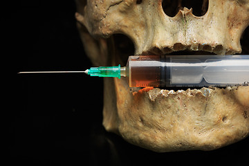 Image showing Skull and syringe of yellowish liquid. concept drugs