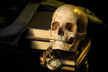 Image showing human skull on a book next to the clock. concept of black magic