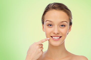 Image showing happy young woman pointing finger to her teeth