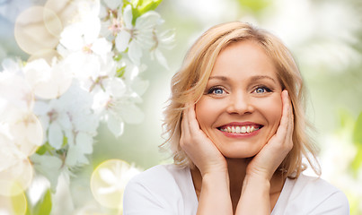 Image showing smiling woman in white t-shirt touching her face