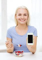 Image showing woman with smartphone eating fruits at home