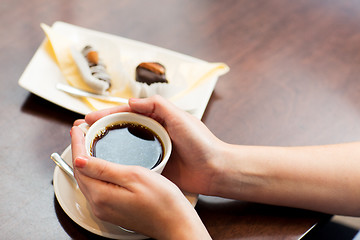 Image showing close up of woman holding coffee cup and dessert