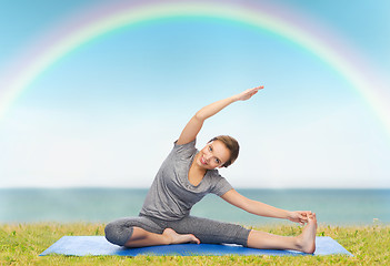 Image showing happy woman making yoga and stretching on mat