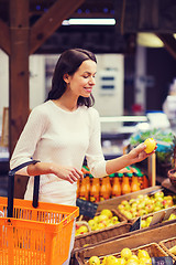 Image showing happy young woman with food basket in market