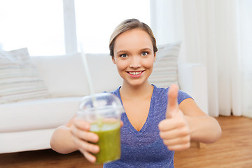Image showing happy woman with cup of smoothie showing thumbs up