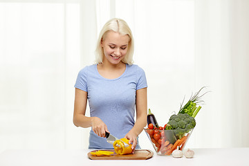 Image showing smiling young woman chopping vegetables at home