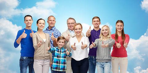 Image showing happy people showing thumbs up over sky and clouds
