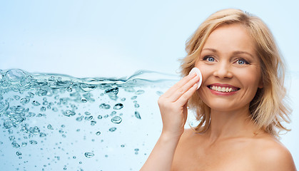 Image showing happy woman cleaning face with cotton pad