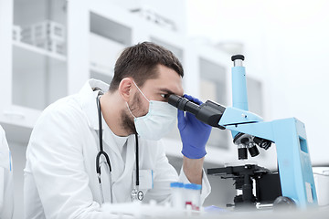 Image showing young scientist looking to microscope in lab