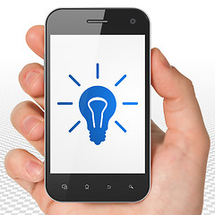 Image showing Business concept: Hand Holding Smartphone with Light Bulb on display