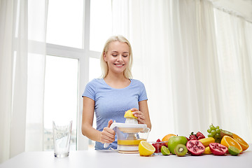 Image showing smiling woman squeezing fruit juice at home