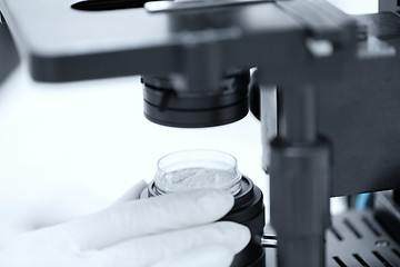Image showing close up of hand with microscope and powder sample