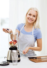 Image showing smiling woman with blender preparing shake at home