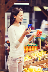 Image showing happy woman with smartphone and tomato in market