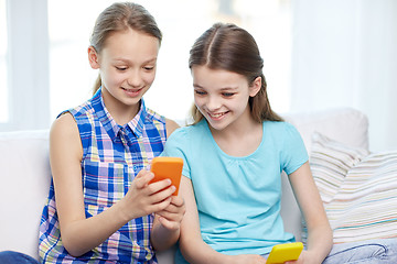 Image showing happy girls with smartphones sitting on sofa