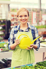 Image showing happy woman with watering can in greenhouse