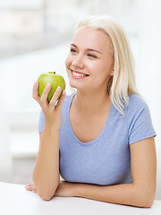 Image showing happy woman eating green apple at home