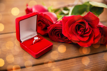 Image showing close up of diamond engagement ring and red roses