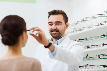 Image showing optician putting glasses to woman at optics store