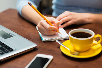 Image showing close up of woman writing to notebook with pencil