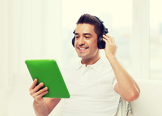 Image showing smiling man with tablet pc and headphones at home