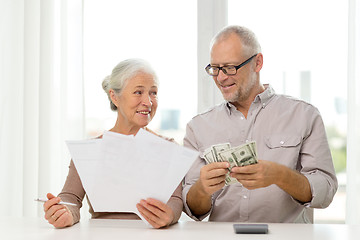 Image showing senior couple with money and calculator at home