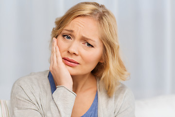 Image showing unhappy woman suffering toothache at home