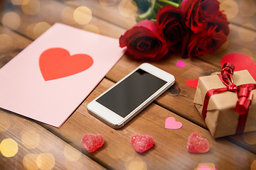 Image showing close up of smartphone, gift, red roses and hearts