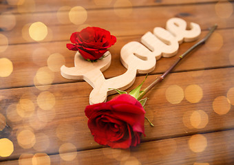 Image showing close up of word love cutout with red rose on wood