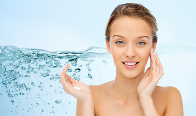 Image showing smiling young woman applying cream to her face