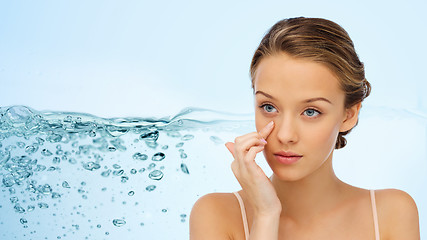 Image showing young woman applying cream to her face