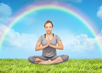 Image showing woman meditating in lotus yoga pose over rainbow 