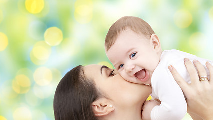 Image showing happy mother kissing her baby over green lights