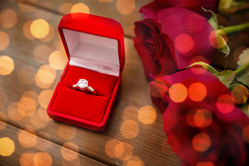 Image showing close up of diamond engagement ring and red roses