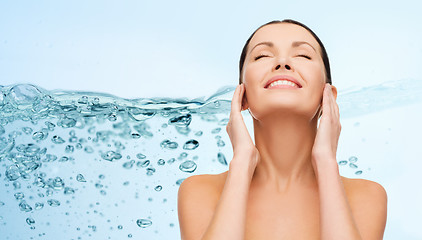 Image showing smiling young woman cleaning her face over water