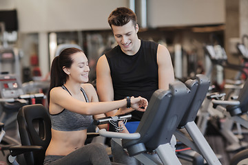 Image showing happy woman with trainer on exercise bike in gym